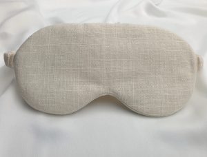 Soft ivory sleep mask made from natural linen and silk on a silk background