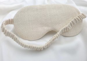 Ivory linen sleep mask with elastic band on soft silk background